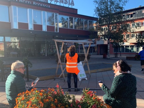två personer sitter på en bänk och tittar på sina mobiler. 