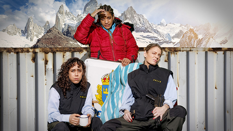 De tre medverkande i vinterkläder mot en bakgrund av fjäll-toppar. De håller en skylt med Tre Kronor på, som delvis döljs av chilenska flaggan.)