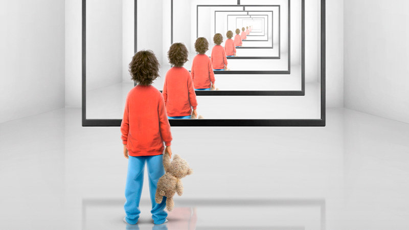 Ett barn står framför en stor teveskärm, på vilken bilden av barnet framför skärmen visas, vilket skapar en illusion av en evighetsspegel.)