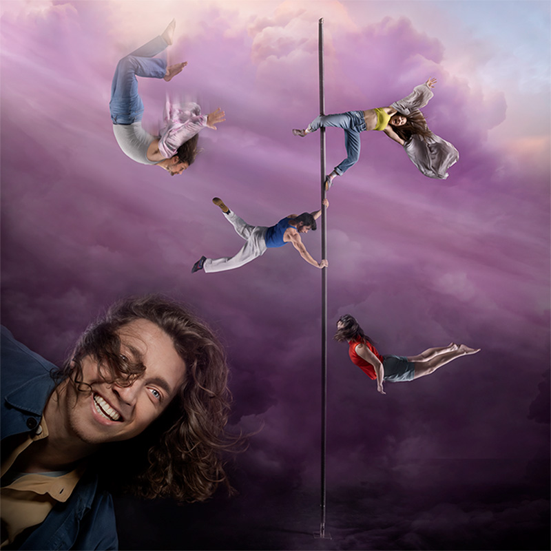 En himmel med stormiga moln i lila. Till vänster en man med stort leende och lockigt hår, till höger en lång påle med fyra akrobater i olika poser.