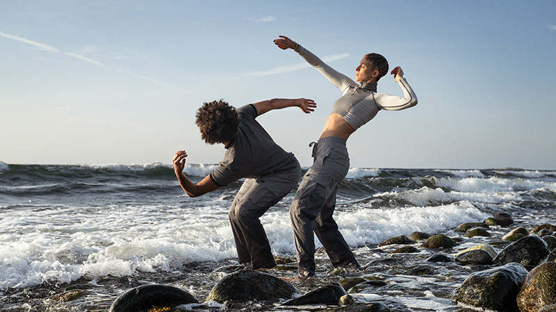 Två dansare fångade i en pose vid strandbrynet)